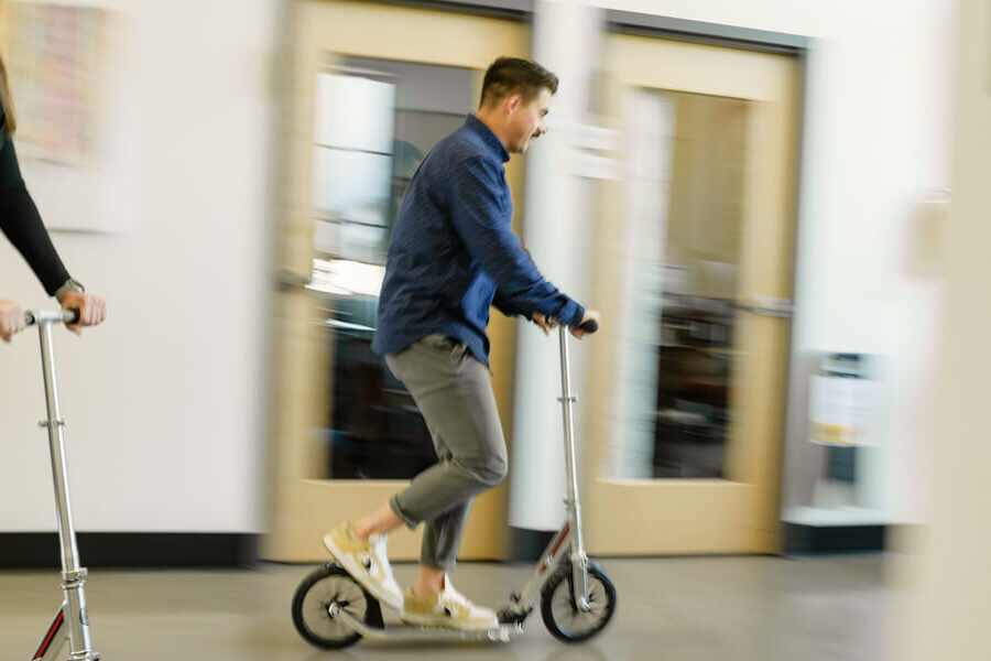Jo Cagle riding a scooter through the halls of the PIE office